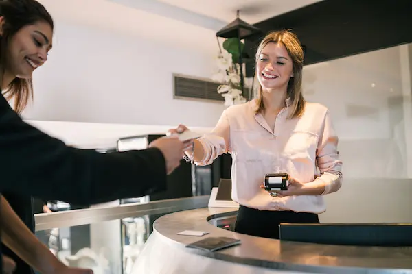 Woman at the front desk of a hotel checking in a guest